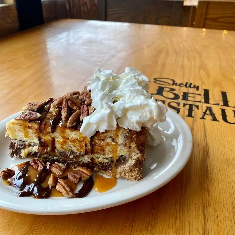 Pecan caramel chocolate cheesecake slice with whipped cream