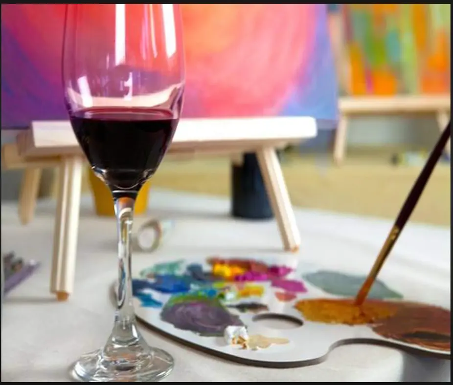 Red wine glass near artist's palette and brush