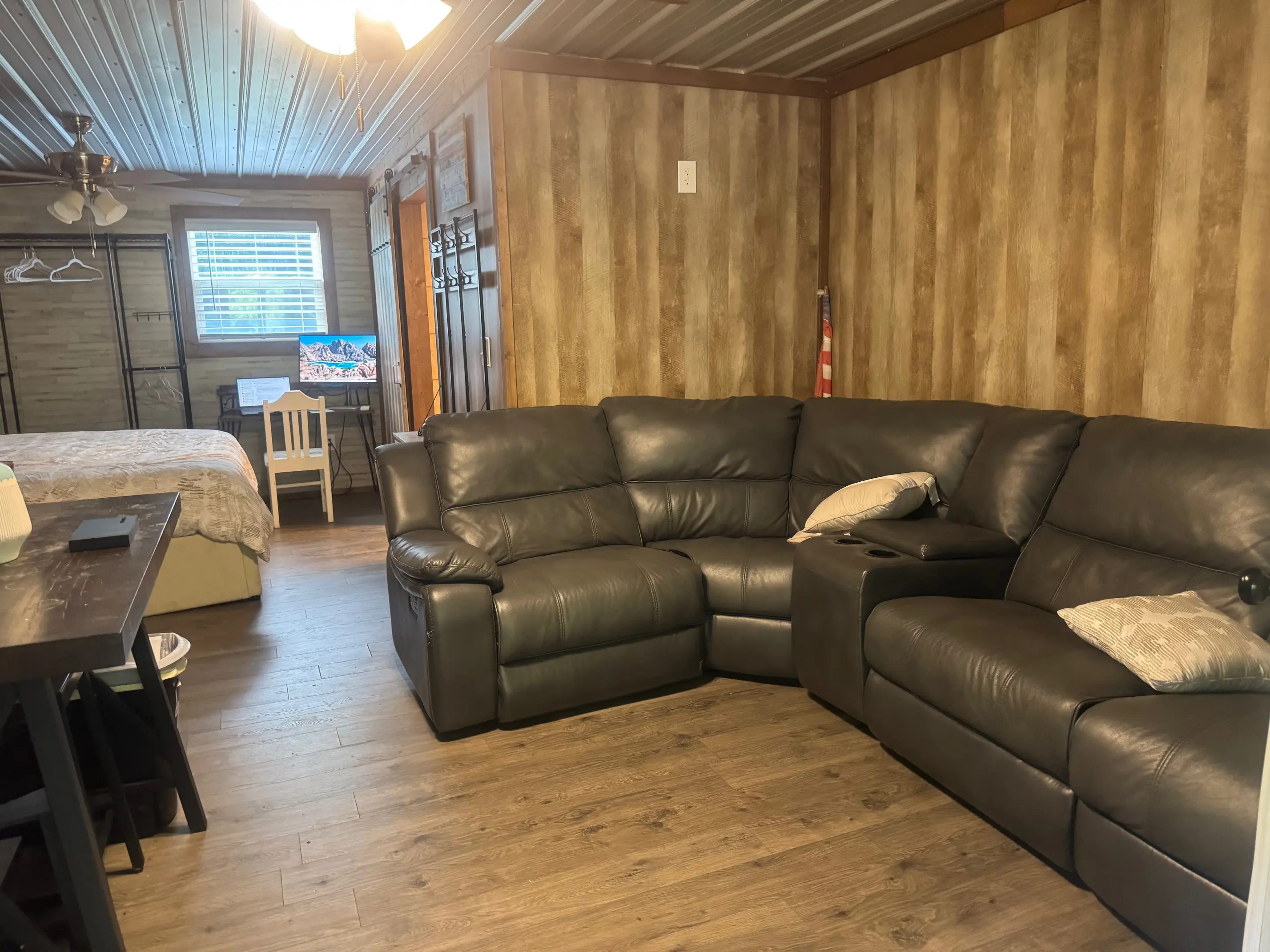 Wood-paneled studio with dark leather sectional sofa