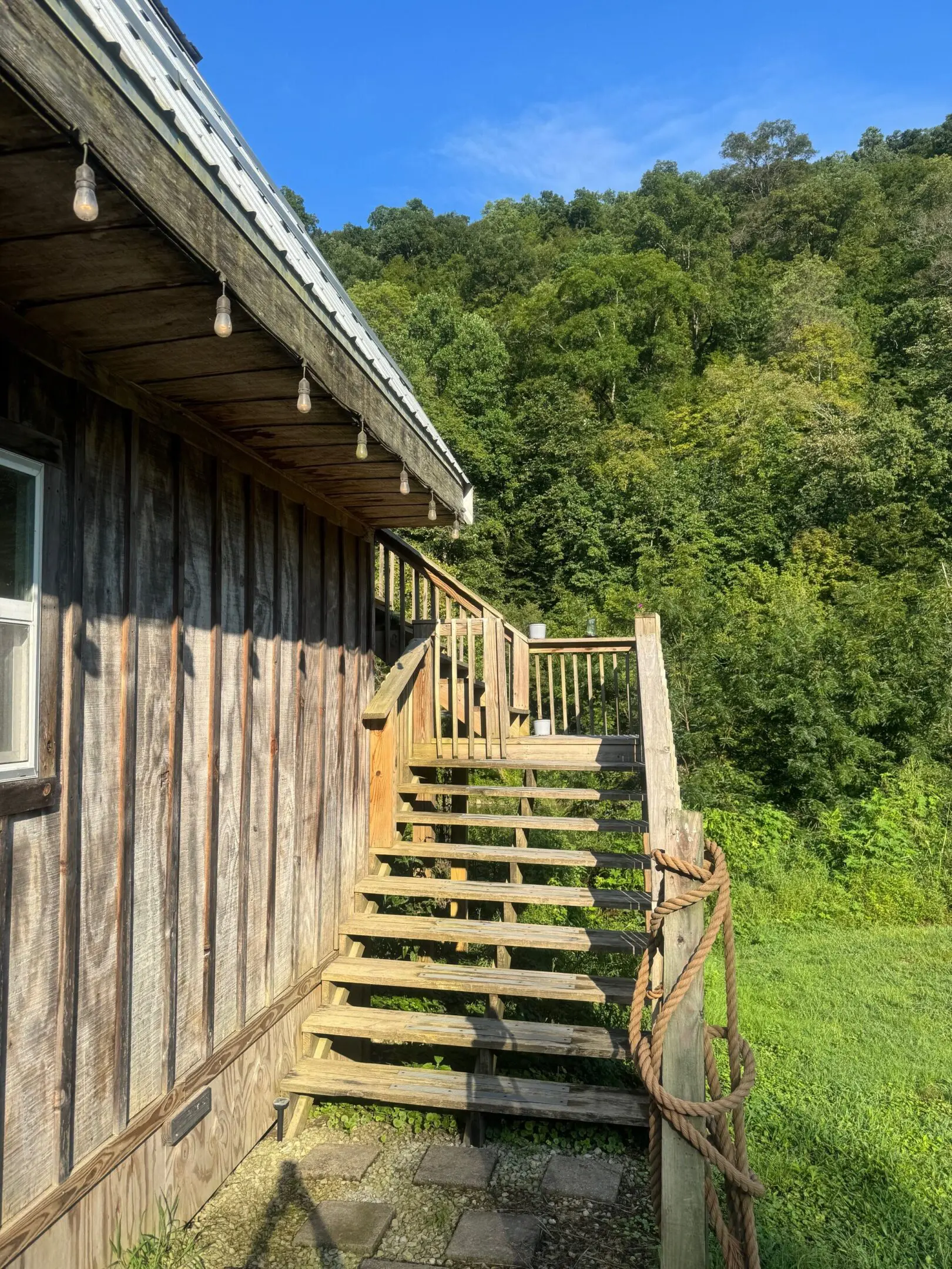 Wooden stairs beside cabin overlooking green hillside