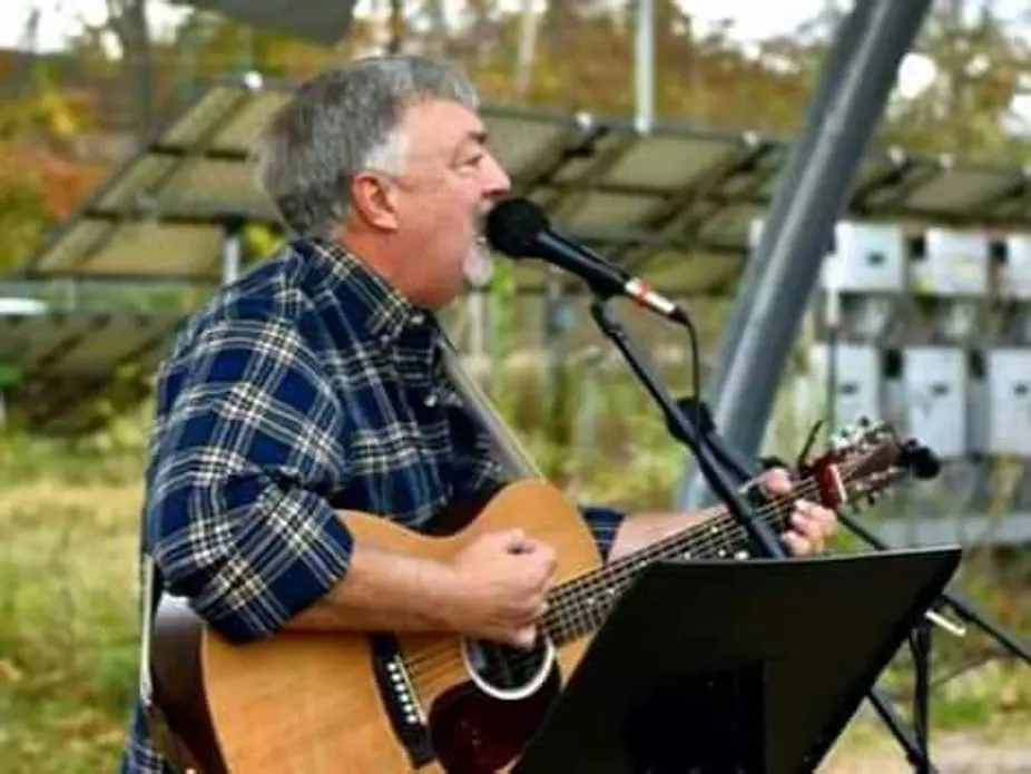 Man singing and playing acoustic guitar outdoors