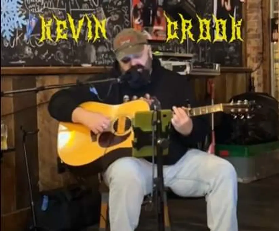 Bearded musician playing acoustic guitar on stage