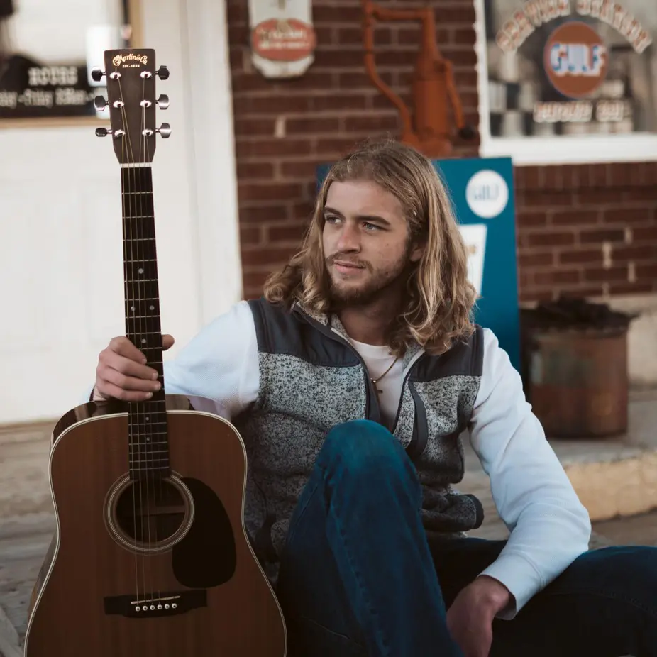 Man sitting outdoors with acoustic guitar