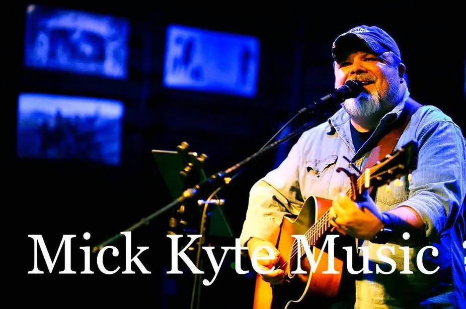 Bearded singer playing acoustic guitar at microphone