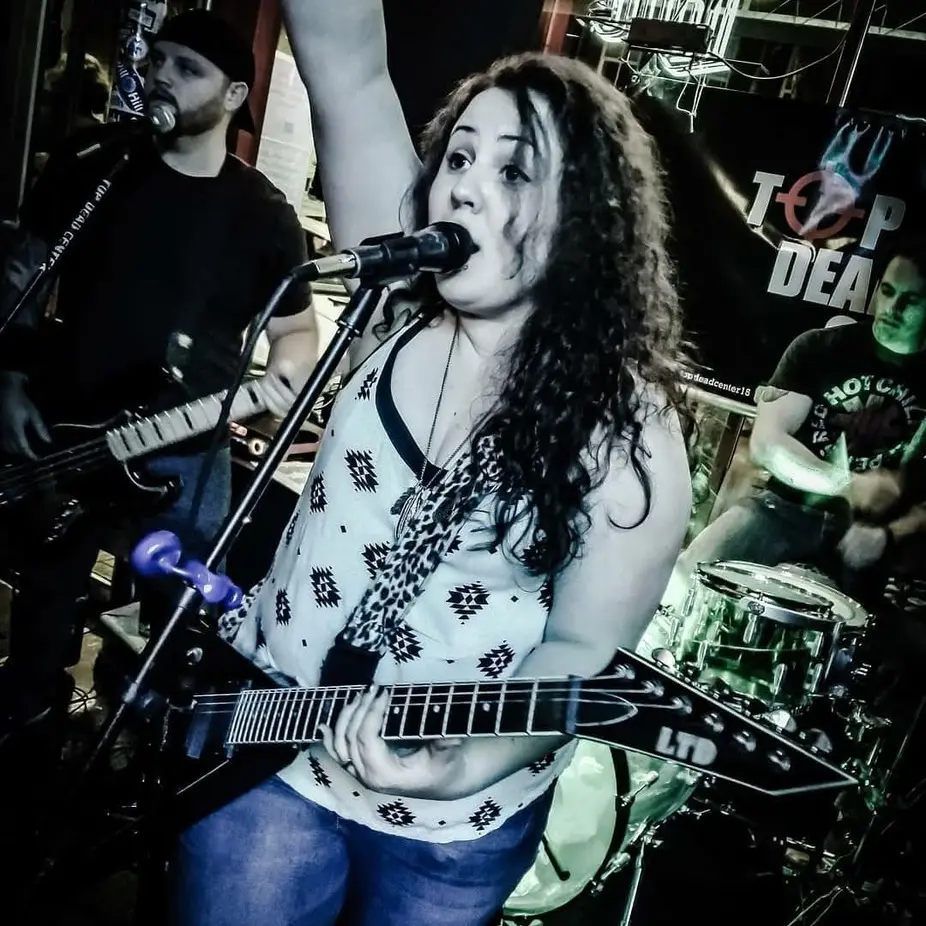 Female singer with raised arm playing electric guitar