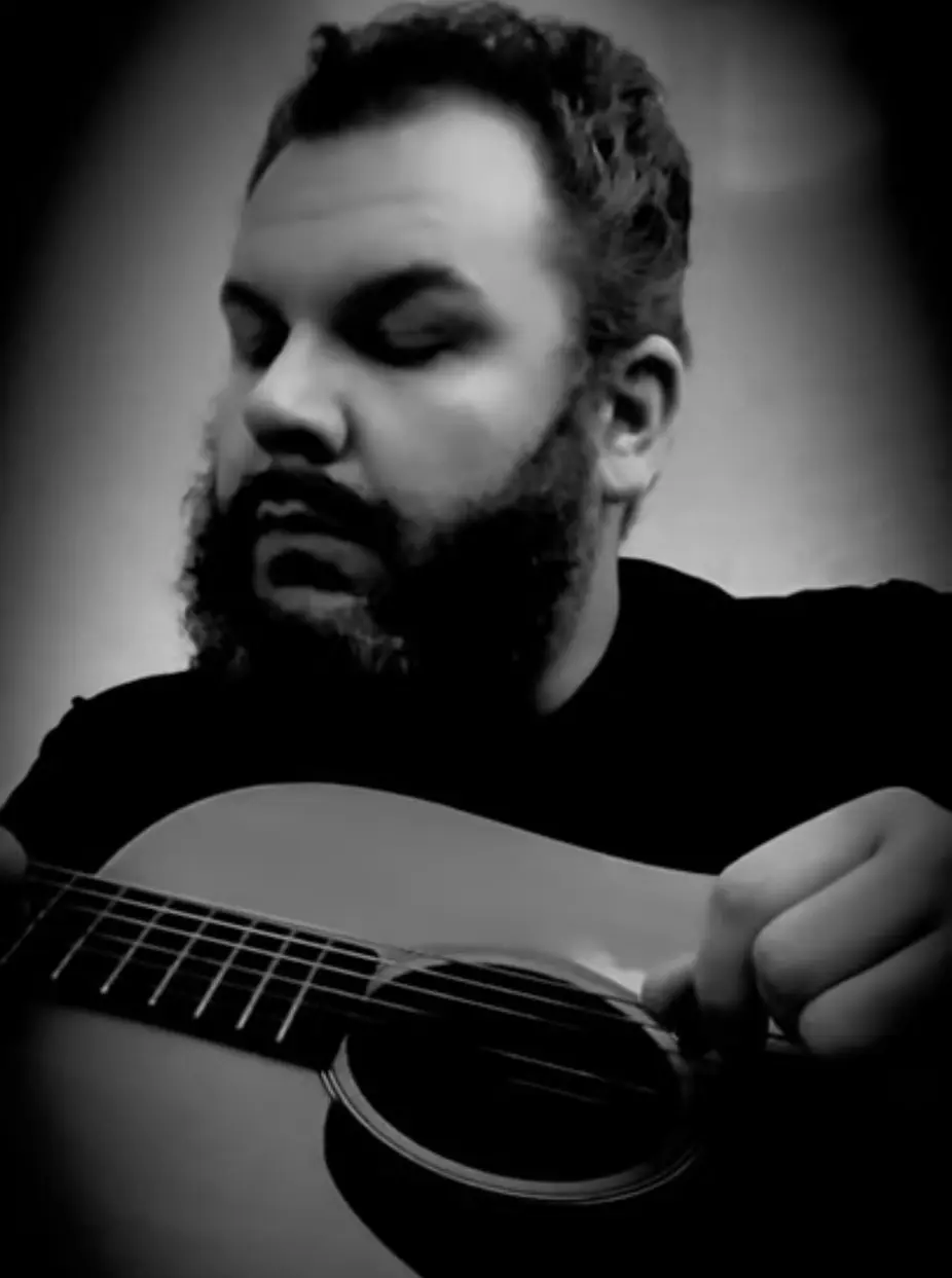 Bearded man playing acoustic guitar, black-and-white