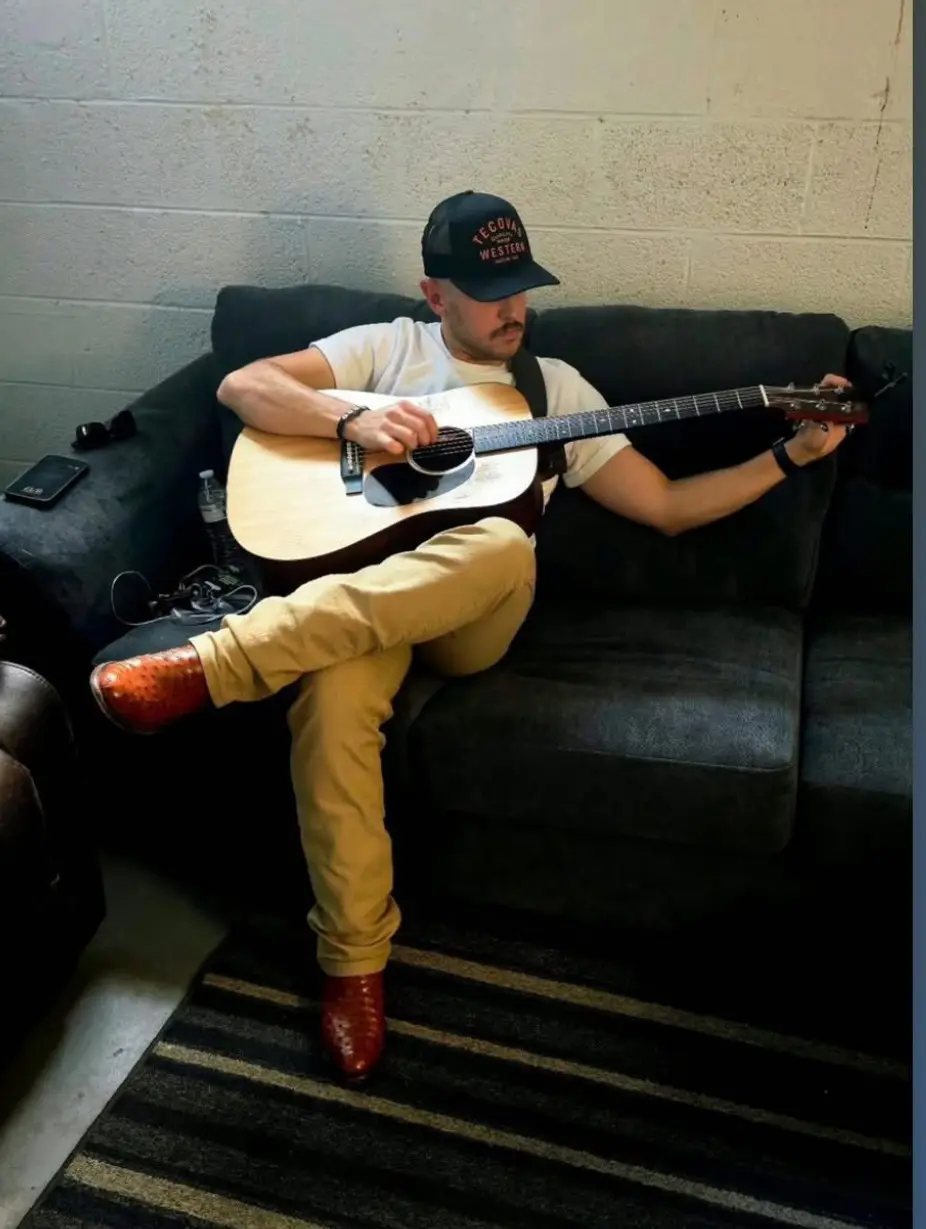 Person playing acoustic guitar on couch